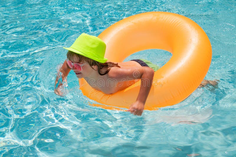 Child swin in swimming pool on inflatable ring. Kid swim with orange float. Water toy, healthy outdoor sport activity. For children. Fashion summer kids in hat
