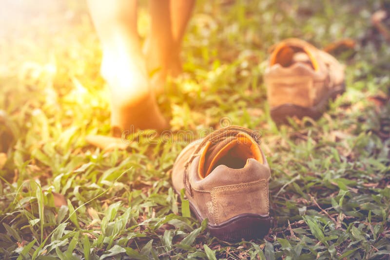 Child take off shoes. Child`s foot learns to walk on grass with