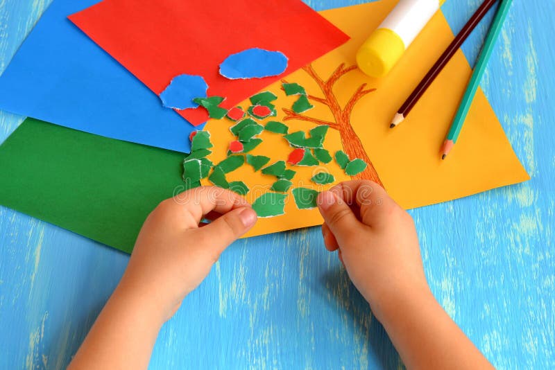 Child tearing colored paper into pieces. Home activity to improve fine motor skill development. Baby play. How to work with paper stock photography