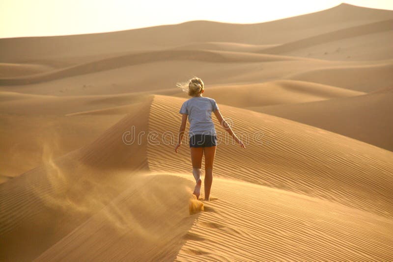 Child walking away on a sand dune