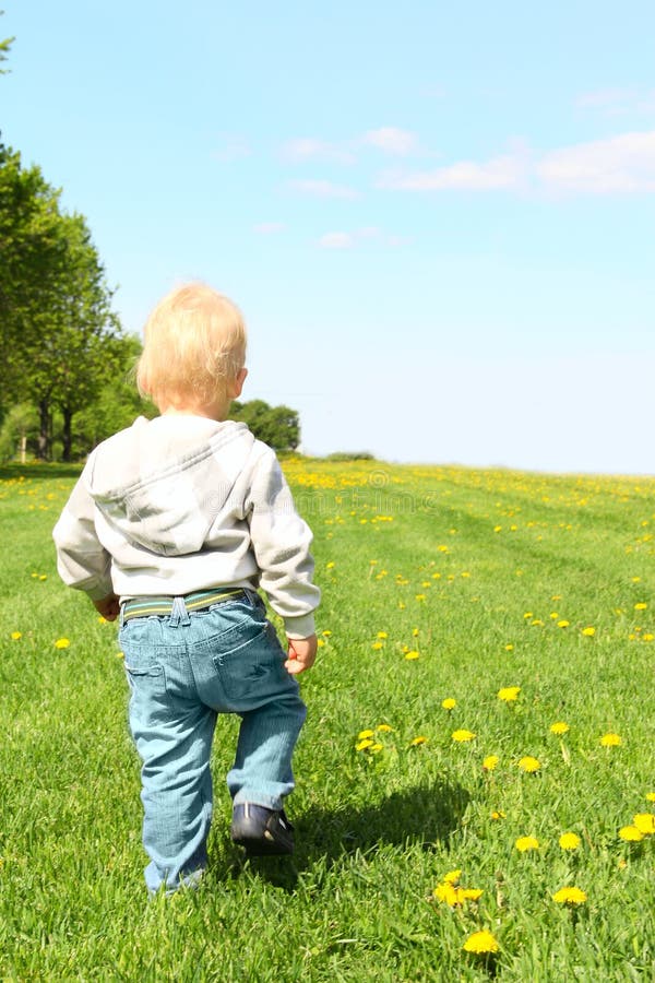 Child walking on green field
