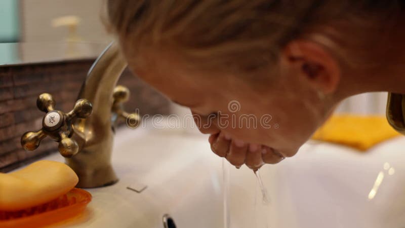 Child wash toothbrush and rinse mouth at bathroom faucet