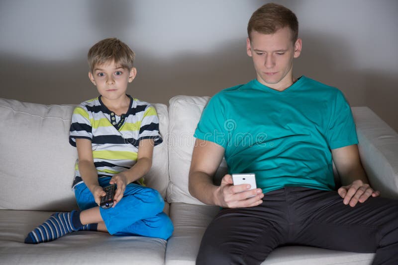 Child watching tv and dad using phone royalty free stock photo Child watching tv and dad using phone royalty free stock photo