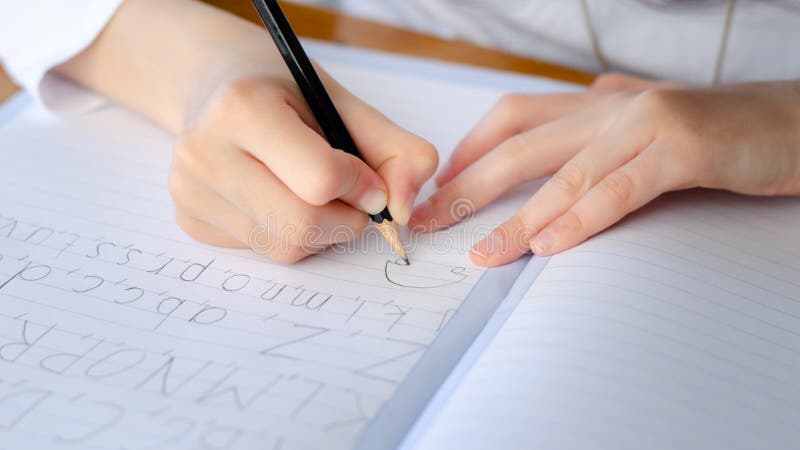 Child writing alphabet in notebook during Corona virus lock down