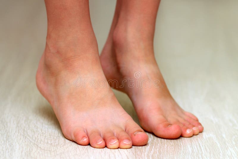 Child& x27;s feet on parquet laminate wooden texture floor close-up.