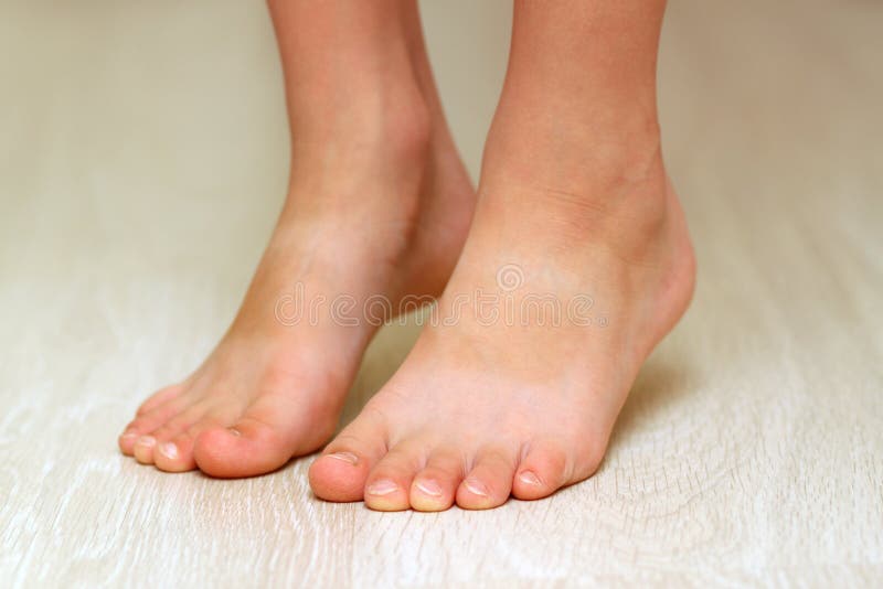 Child& x27;s feet on parquet laminate wooden texture floor close-up.