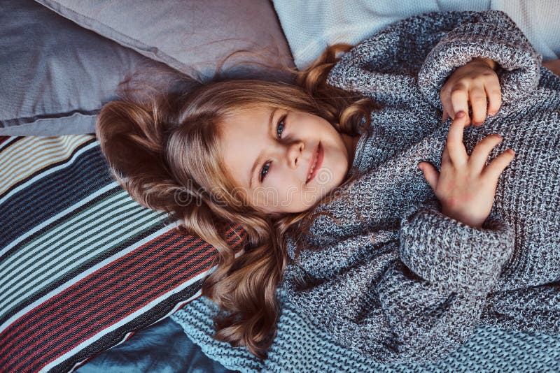 Close-up portrait of a little girl in warm sweater lying on bed. stock photography Close-up portrait of a little girl in warm sweater lying on bed. stock photography