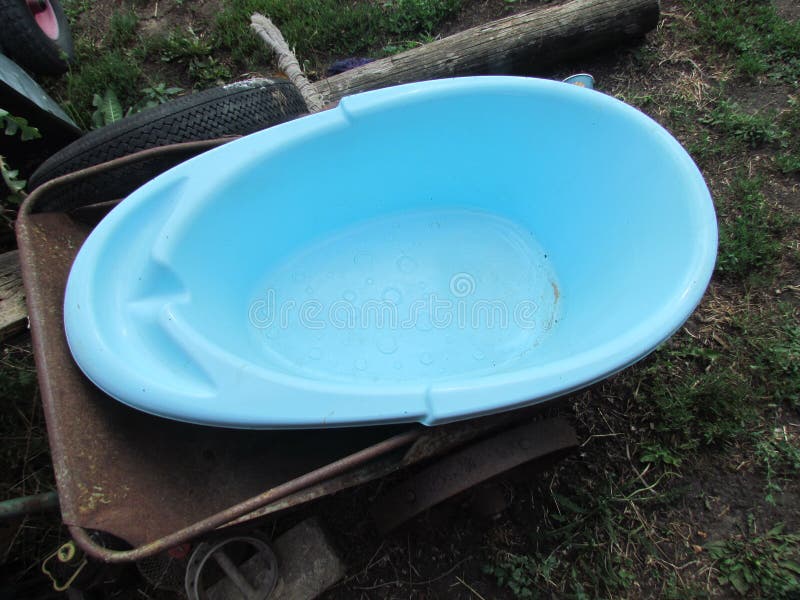 A childhood Turkish blue plastic bath is lying in an old metal cart. A childhood Turkish blue plastic bath is lying in an old metal cart