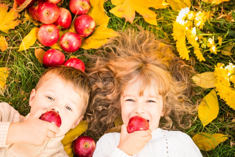 Happy children lying on fall leaves. Funny kids outdoors in autumn park. Happy children lying on fall leaves. Funny kids outdoors in autumn park