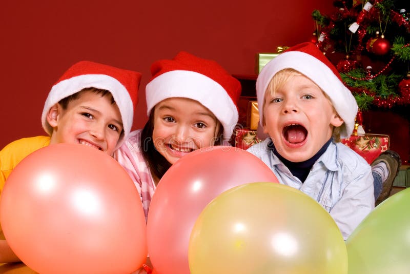 Children with ballons by Christmas tree