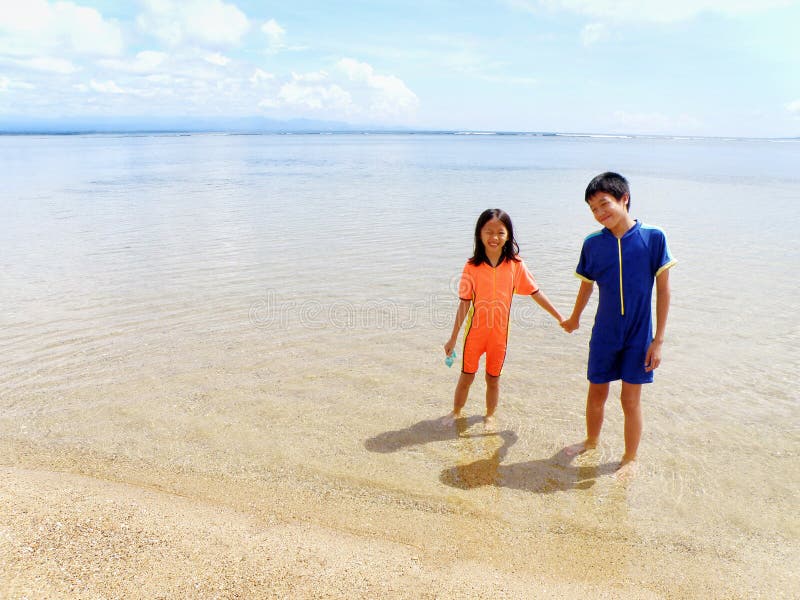 Ein Bild von zwei asiatische chinesische Kinder halten sich an den Händen und Spaß am Meer Strand.