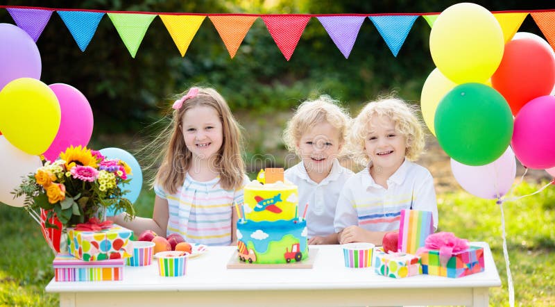 Children blow candles on birthday cake. Kids party. Decoration and food. Boy and girl celebrating birthday of little brother. Transport and car kid event theme stock image Children blow candles on birthday cake. Kids party. Decoration and food. Boy and girl celebrating birthday of little brother. Transport and car kid event theme stock image
