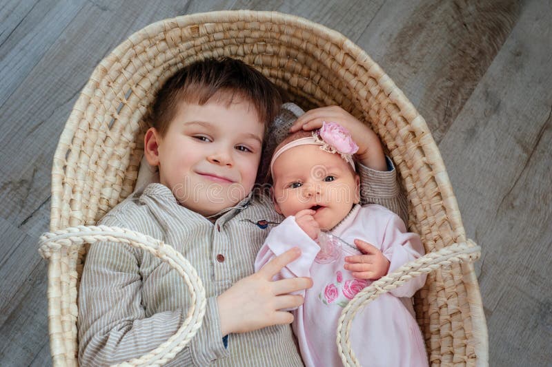 Children, cute little boy 5 years old, with him newborn sister lies in a wicker cradle stock image Children, cute little boy 5 years old, with him newborn sister lies in a wicker cradle stock image