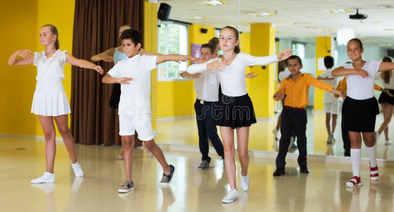 Boys and girls dancing in studio with young women instructor and smiling. Boys and girls dancing in studio with young women instructor and smiling