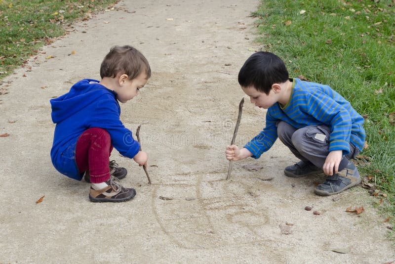 Children drawing into sand stock photography