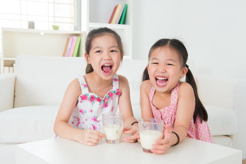 Children drinking milk. Asian family at home. Beautiful sister drinks milk together.