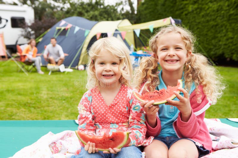 Children Enjoying Picnic Whilst On Family Camping Holiday Smiling