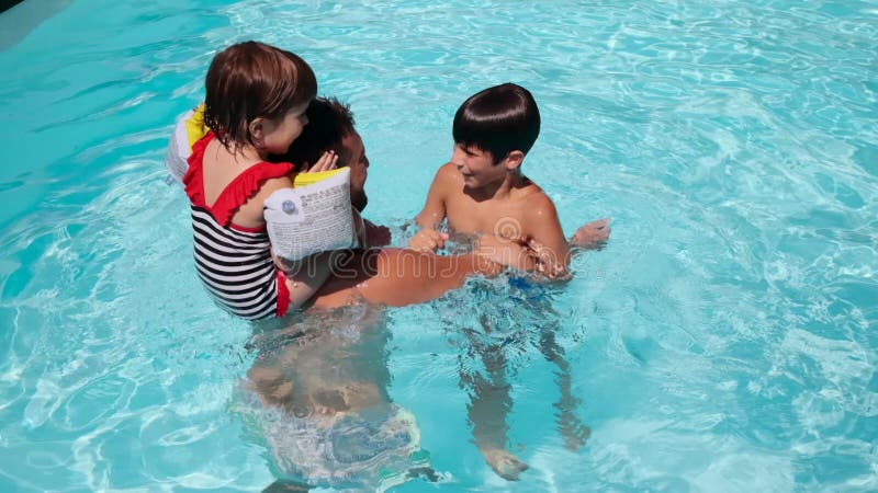 Children playing with father in swimming pool