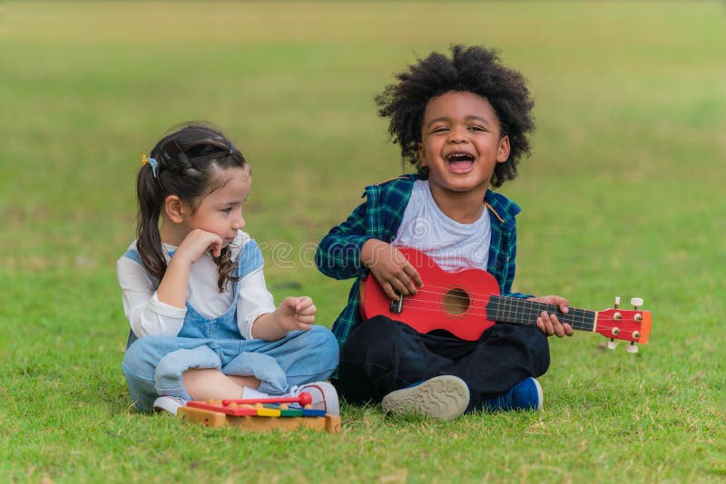 Children friends have fun together playing musical toy in park during summer