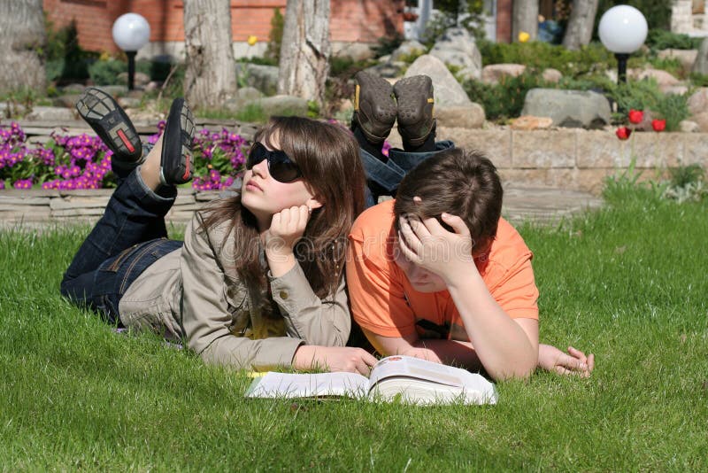 A dreaming girl lying on the grass with a boy which are reading a book. Reading efficiency stock images, royalty-free photos and pictures