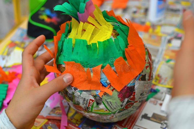 Children hands are making a pinata with colorful paper and glue. Children hands are making a pinata with colorful paper and glue.