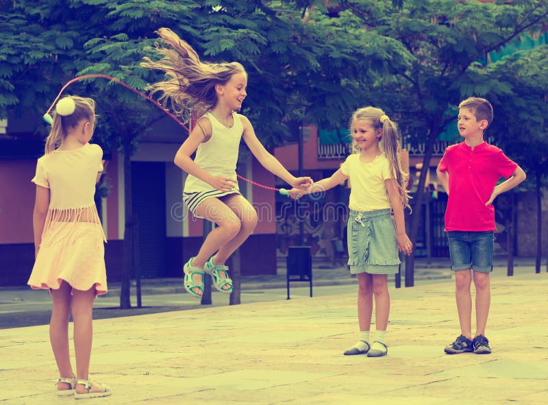 Portrait of happy children skipping together with jumping rope on urban playground. Portrait of happy children skipping together with jumping rope on urban playground