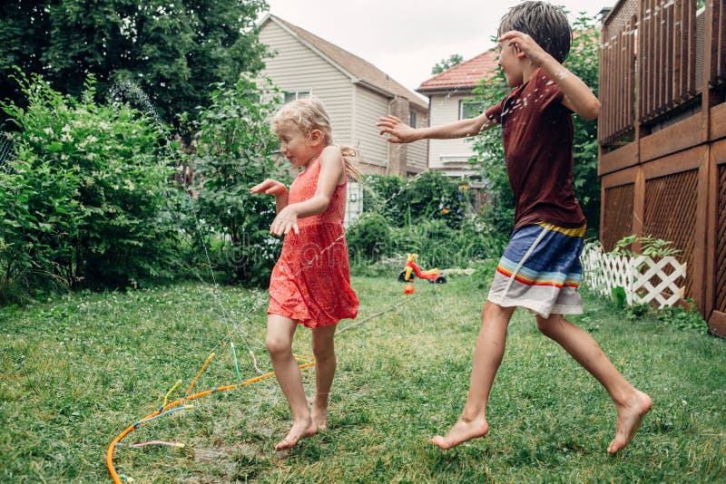 Children kids splashing with gardening hose sprinkler on backyard on summer day stock images Children kids splashing with gardening hose sprinkler on backyard on summer day stock images