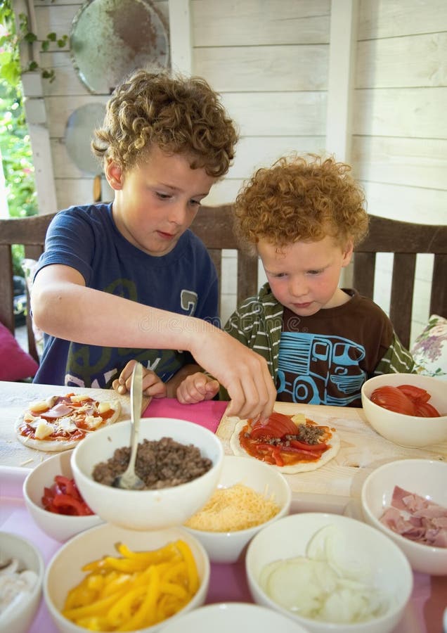 Zwei Brüder (7 und 3) Spaß Kochen, machen Ihre eigenen pizzas, der ältere Bruder helfen den jüngeren.