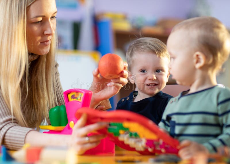 Children and nursery teacher play with toy scales in kindergarten playroom royalty free stock photo Children and nursery teacher play with toy scales in kindergarten playroom royalty free stock photo