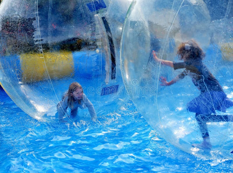 Children play inside of transparent plastic balls