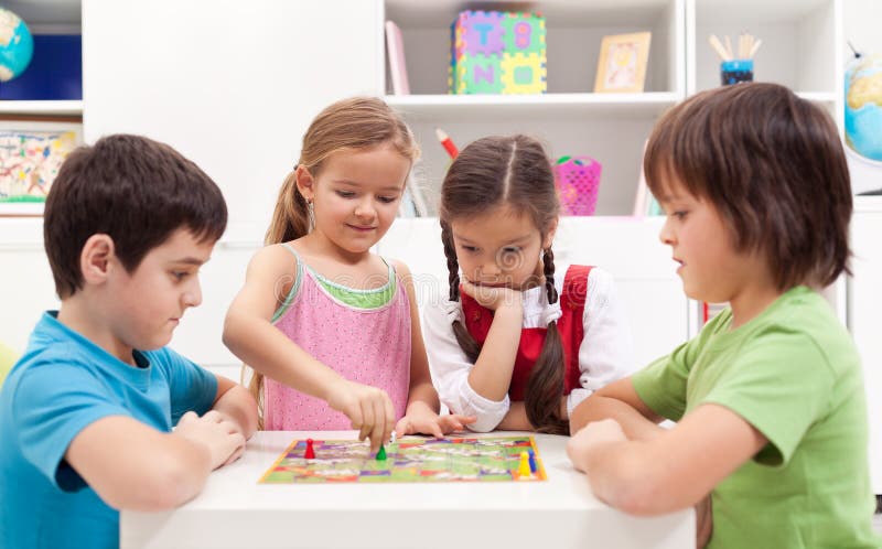 Bambini che giocano gioco da tavolo, seduti intorno ad un tavolino.