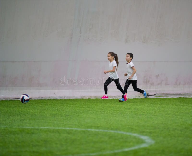 Children playing football indoors. A little girl and boy playing royalty free stock images Children playing football indoors. A little girl and boy playing royalty free stock images