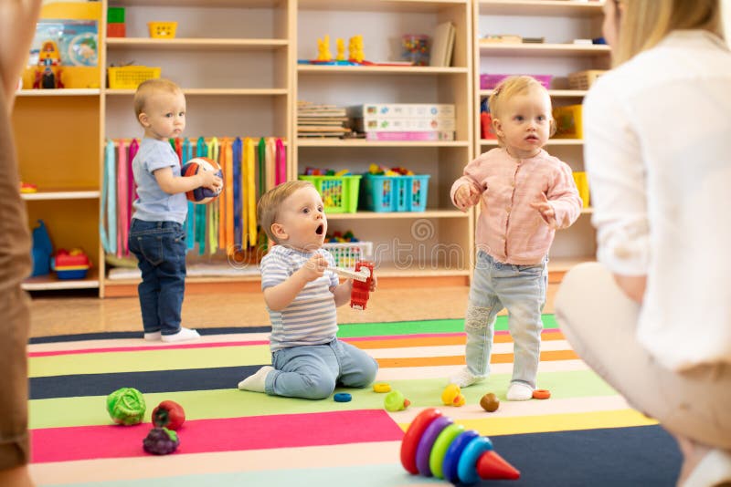 Nursery babies play on floor with carers or mothers in day care centre