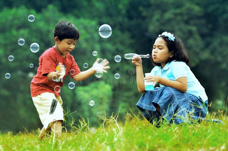 Bambini che giocano con le bolle di sapone in un ambiente verde, sfondo.