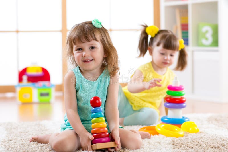 Children playing together. Educational toys for preschool and kindergarten kids. Little girls build pyramid toys at home royalty free stock photo Children playing together. Educational toys for preschool and kindergarten kids. Little girls build pyramid toys at home royalty free stock photo
