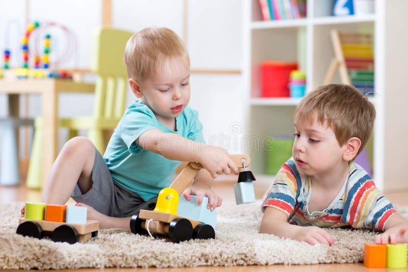 Children playing with wooden car at home or daycare. Educational toys for preschool and kindergarten kid.