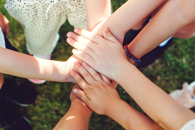 Children putting their hands together outdoors, top view. Group of young people`s hands