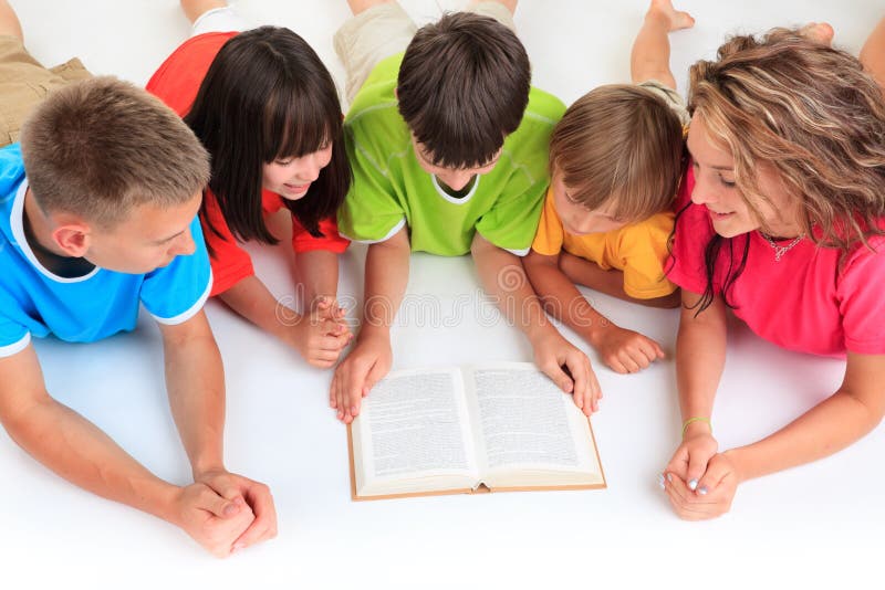 Alto ángulo de cinco a adolescentes en vistoso la ropa lectura un libro común sobre el países, blanco estudio.