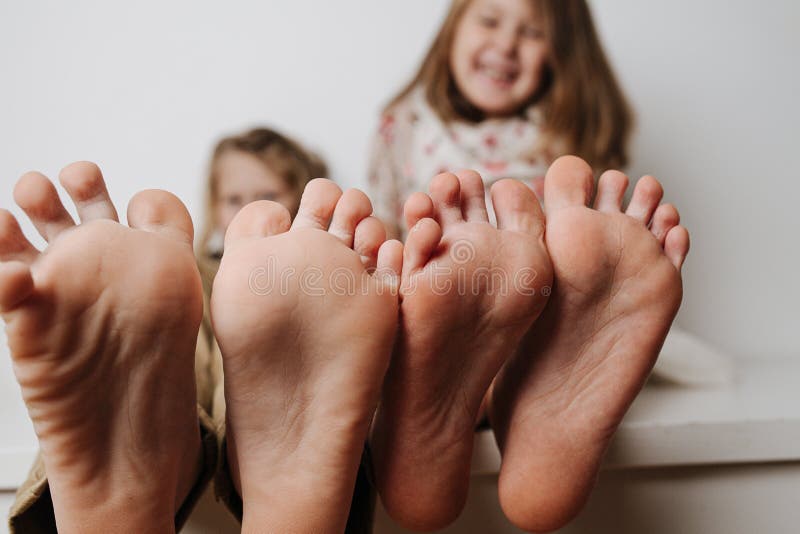 Children`s feet close up to the camera. Their blurred faces in a background.