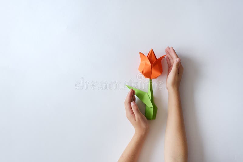 Children`s Hands Do Origami From Colored Paper On White Background