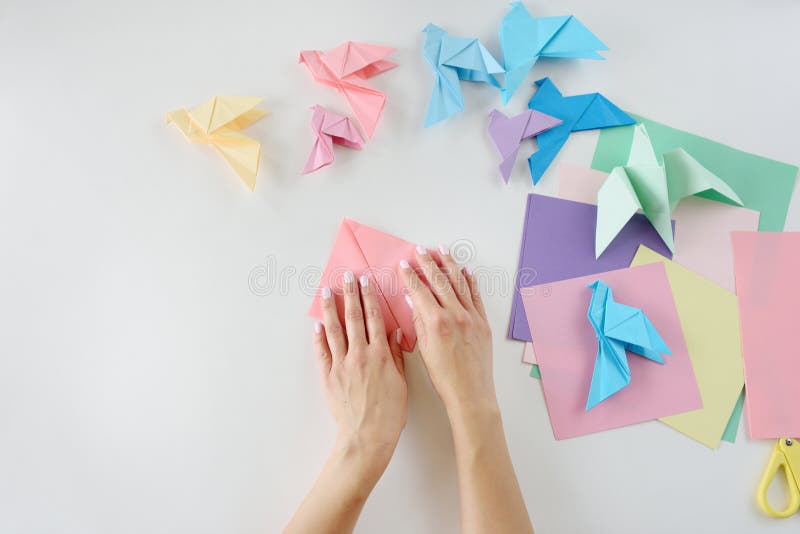 Children`s Hands Do Origami From Colored Paper On White Background