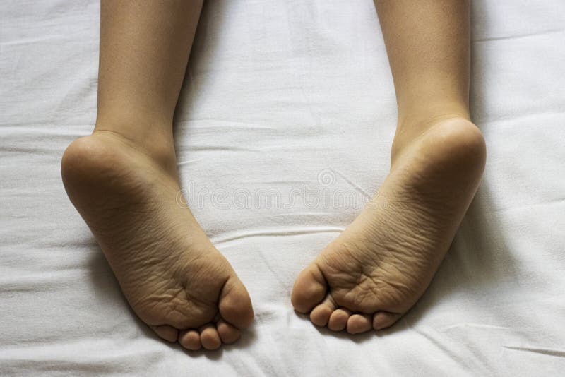 Children`s heels on a white bed close-up