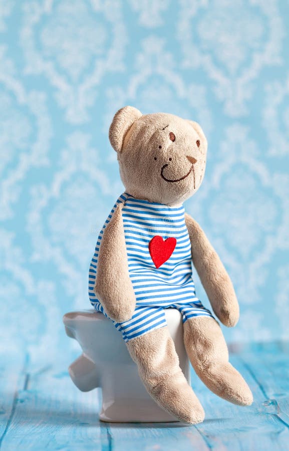 Children s soft toy teddy bear sitting on the toilet in the doll house. Blue bathroom to . Playing with dolls in the