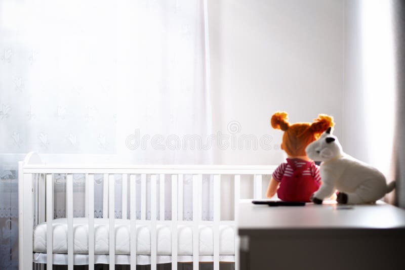 Children`s White Room with an Empty Cradle and Toys on the Dresser