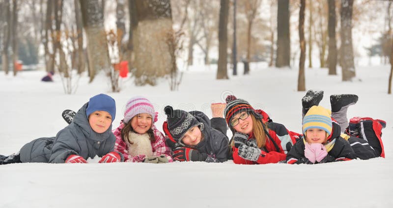 Gruppe von Kindern beim spielen auf Schnee im winter.