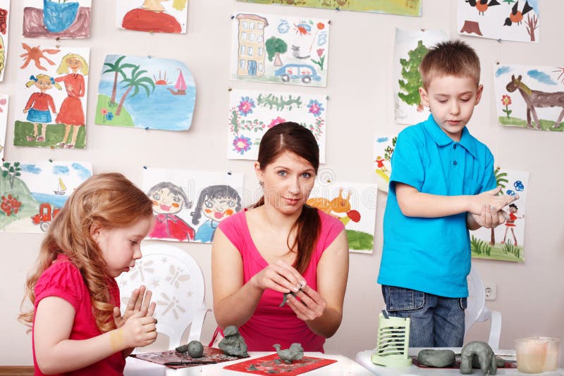 Children and teacher mould from clay in play room.