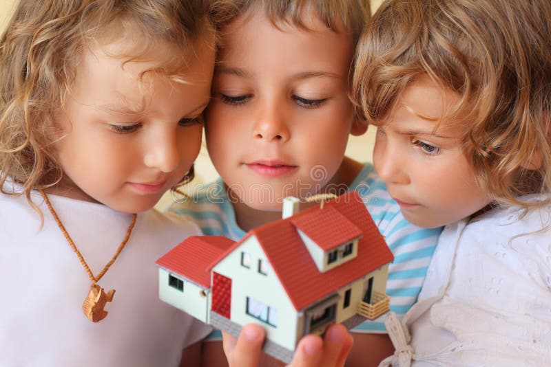 Children together keeping in hands model of house