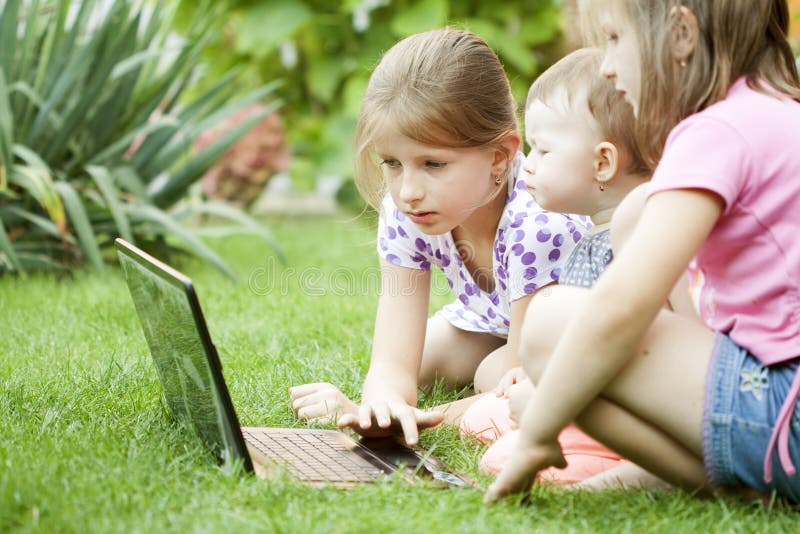 Children using laptop in the meadow