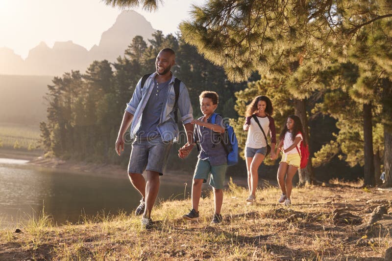 Children Walk By Lake With Parents On Family Hiking Adventure