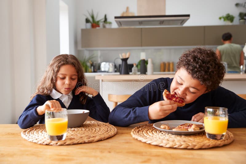 Children Wearing Uniform in Kitchen Eating Breakfast before Going To